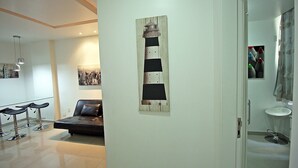Un saló modern amb un sofà negre, una obra d'art de fusta i una porta blanca que dona a un bany.