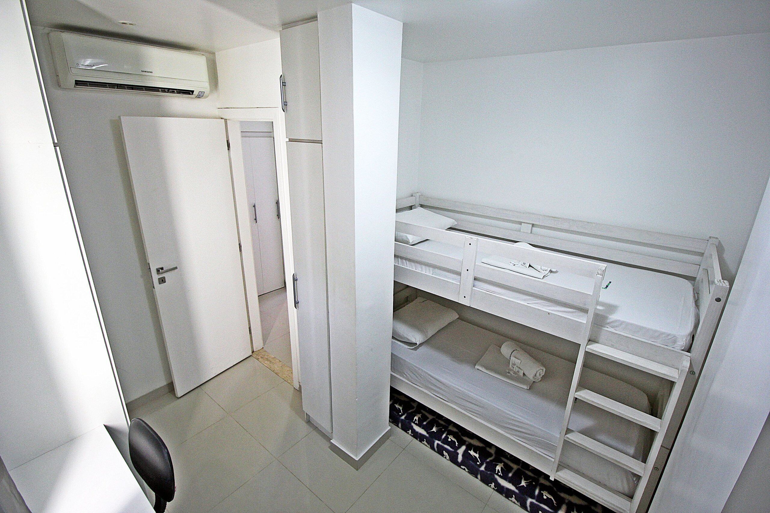 A compact room with a bunk bed, a wardrobe, and a desk.