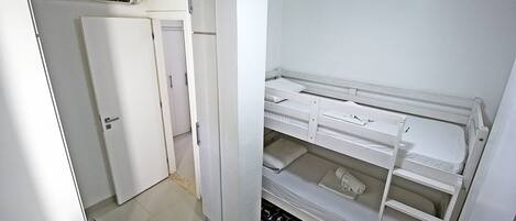 A compact room with a bunk bed, a wardrobe, and a desk.