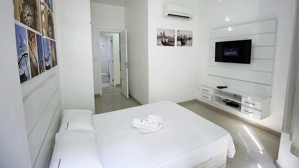 Habitació d'hotel amb llit, televisió i prestatge fixat a la paret.