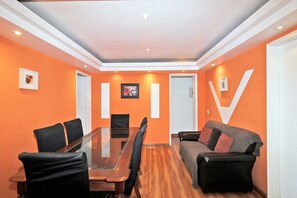 A conference room with a glass table, black chairs, a sofa, and orange walls. - Rio Spot Atlantica 2440 (Rio de Janeiro)