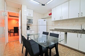 A modern kitchen with white cabinets, a glass dining table, and a microwave. - Rio Spot Atlantica 2440 (Rio de Janeiro)