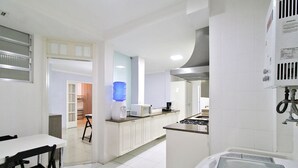 Een moderne keuken met witte kasten, een waterdispenser, een magnetron en een gasfornuis.