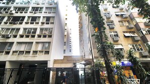 Un edificio de varios pisos con entrada central, unidades de aire acondicionado y balcones.