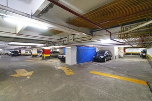 A multi-level parking garage with several cars parked, concrete floors, and visible structural elements like pipes and beams. - Rio Spot Atlantica 2440 (Rio de Janeiro)