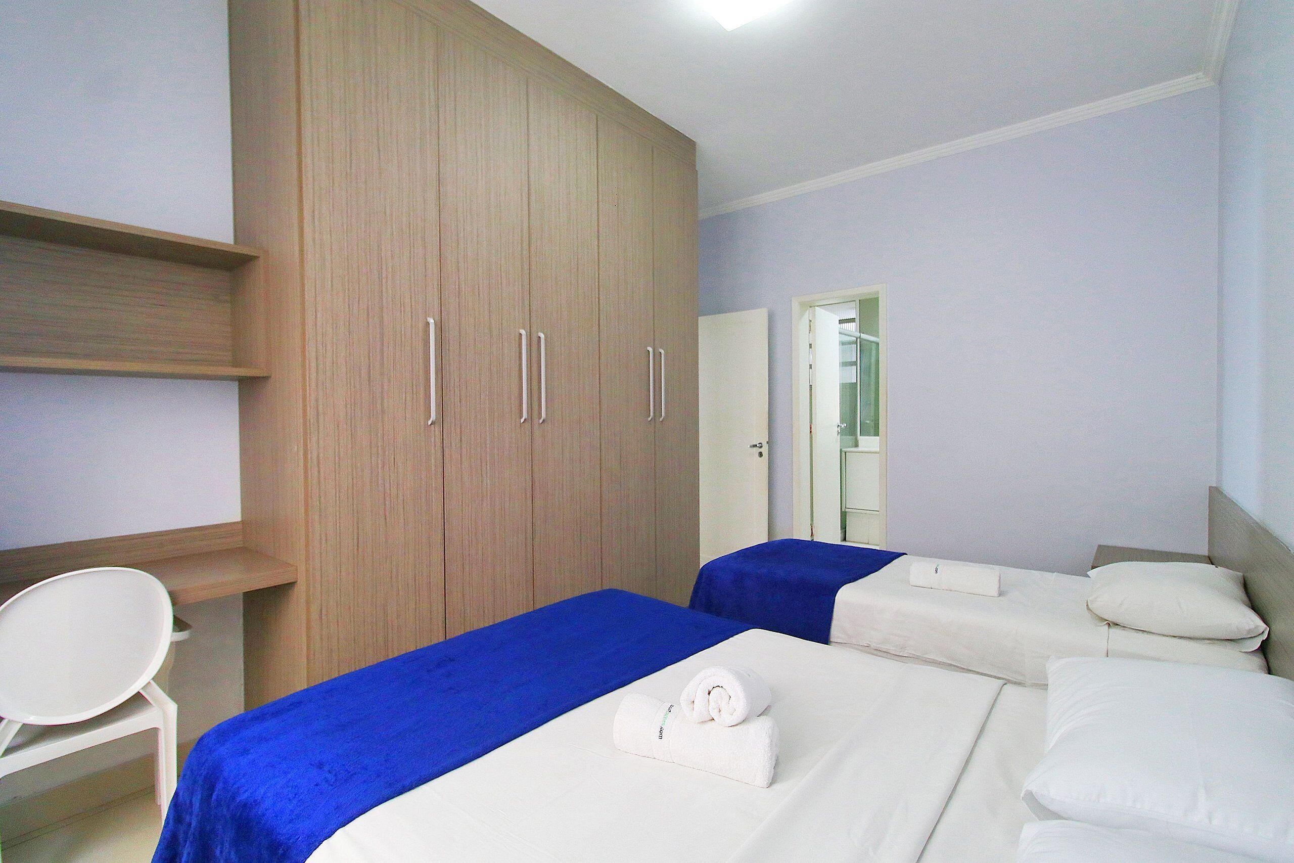 Une chambre d’hôtel avec deux lits, une armoire, un bureau et une chaise.