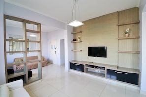 A modern living room with a TV, wooden shelves, and a partition wall. - Rio Spot Atlantica 2440 (Rio de Janeiro)