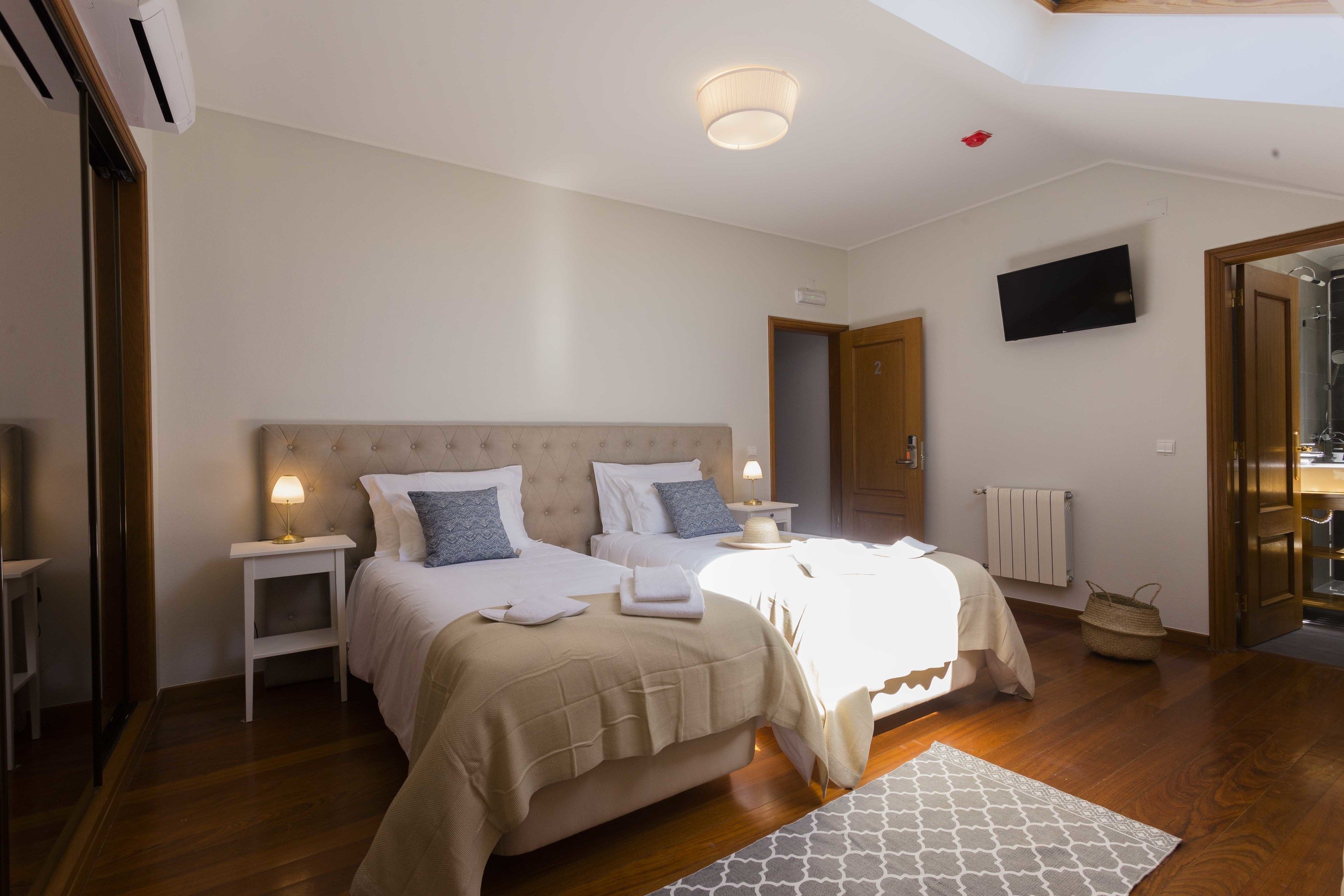A bedroom with two beds, a TV, and a ceiling light.