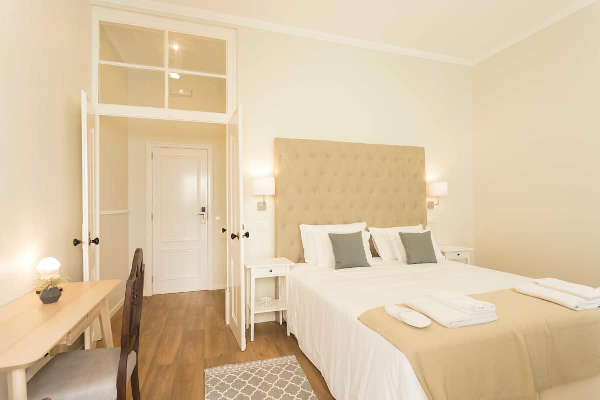 A hotel room with a bed, bedside tables, a desk, and a chair.
