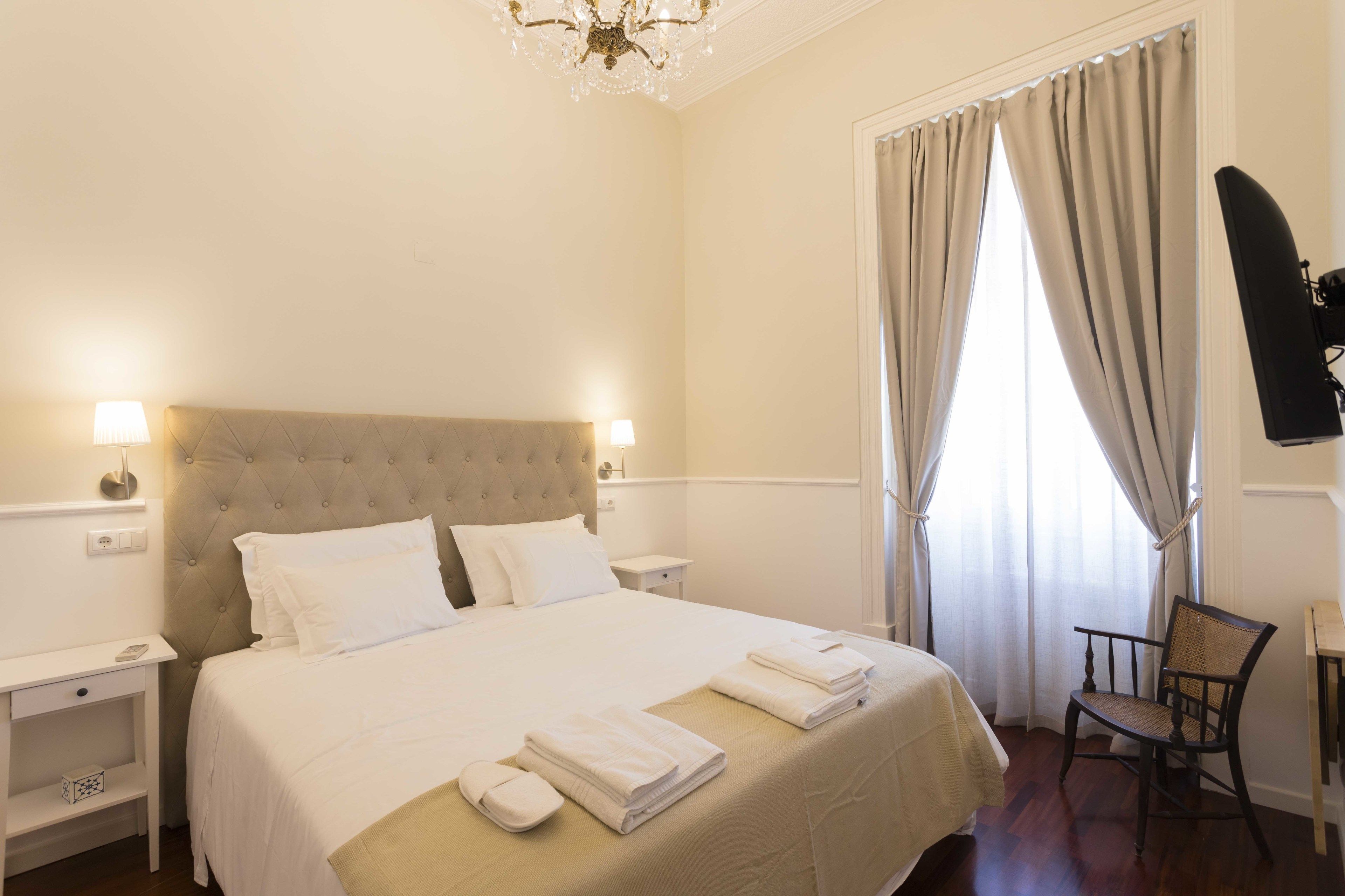 Habitació d'hotel amb un llit gran, dues taules de nit, una cadira i una televisió.