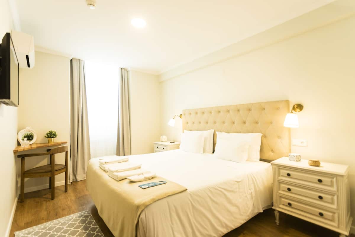 A hotel room with a large bed, bedside tables, a desk, and a chair.