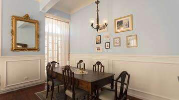 A dining room with a wooden table and chairs, a chandelier, and framed pictures on the wall.