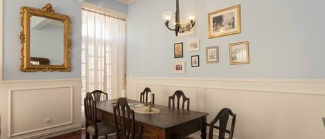 Une salle à manger avec une table et des chaises en bois, un lustre et des tableaux encadrés accrochés au mur.