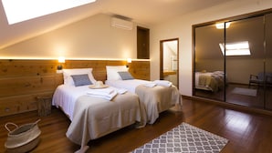 A bedroom with two beds, wooden headboard, skylight, and a large mirror. - Ericeira Soul (Mafra)