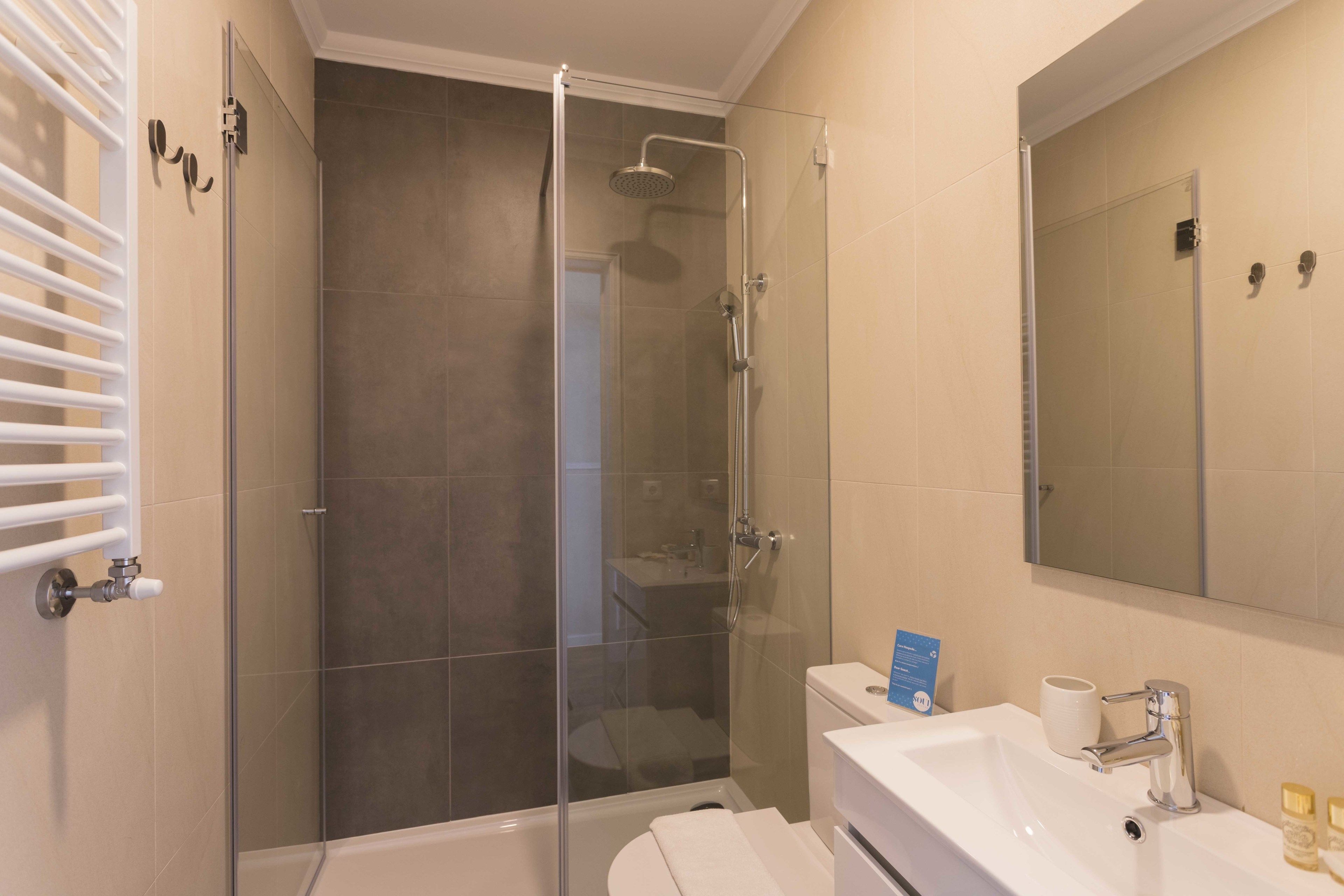 A modern bathroom with a glass-enclosed shower, a white sink, and a large mirror.