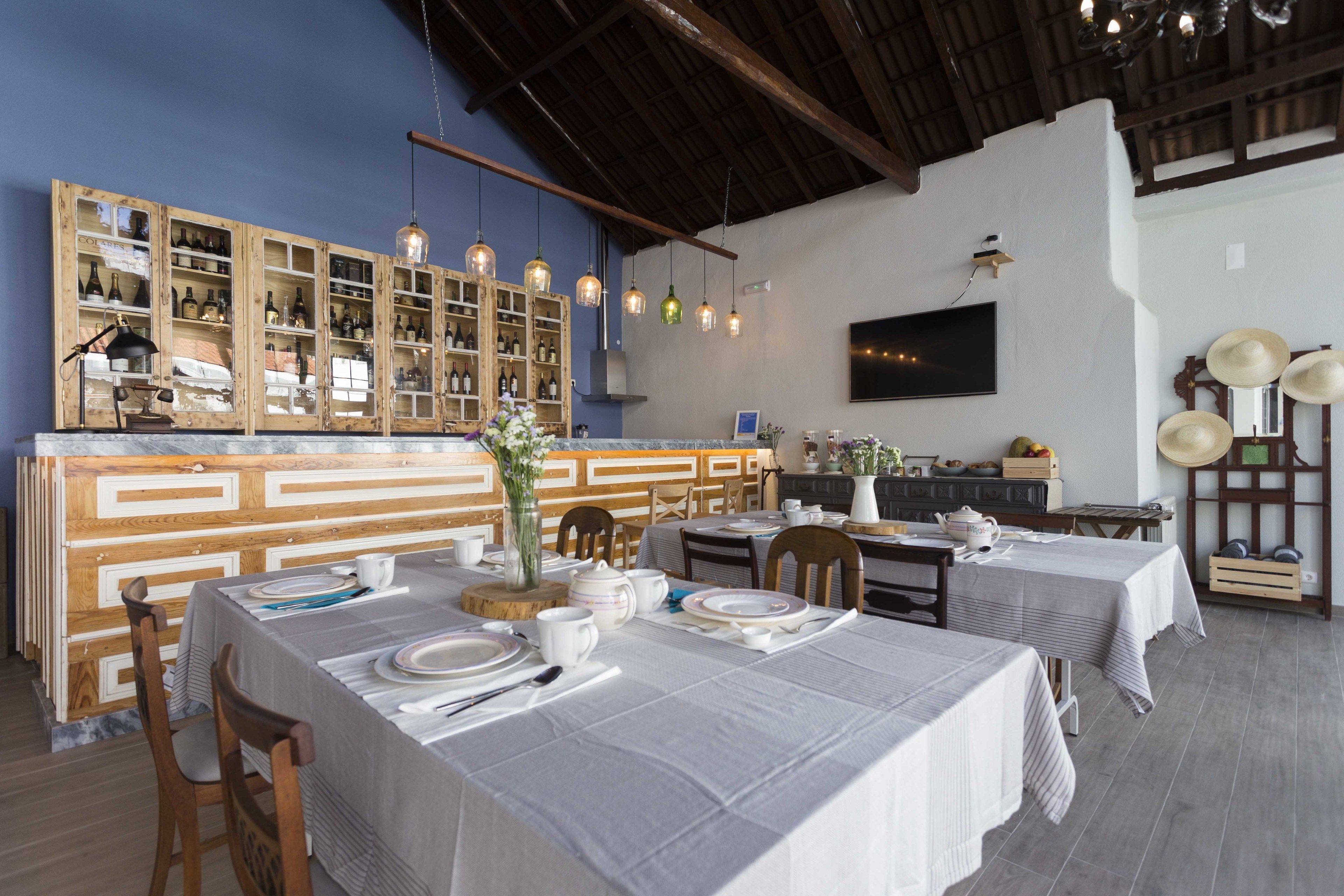 Ein Restaurant mit Holzausstattung, darunter Schränke mit Flaschen, einer Bar und gedeckten Tischen.