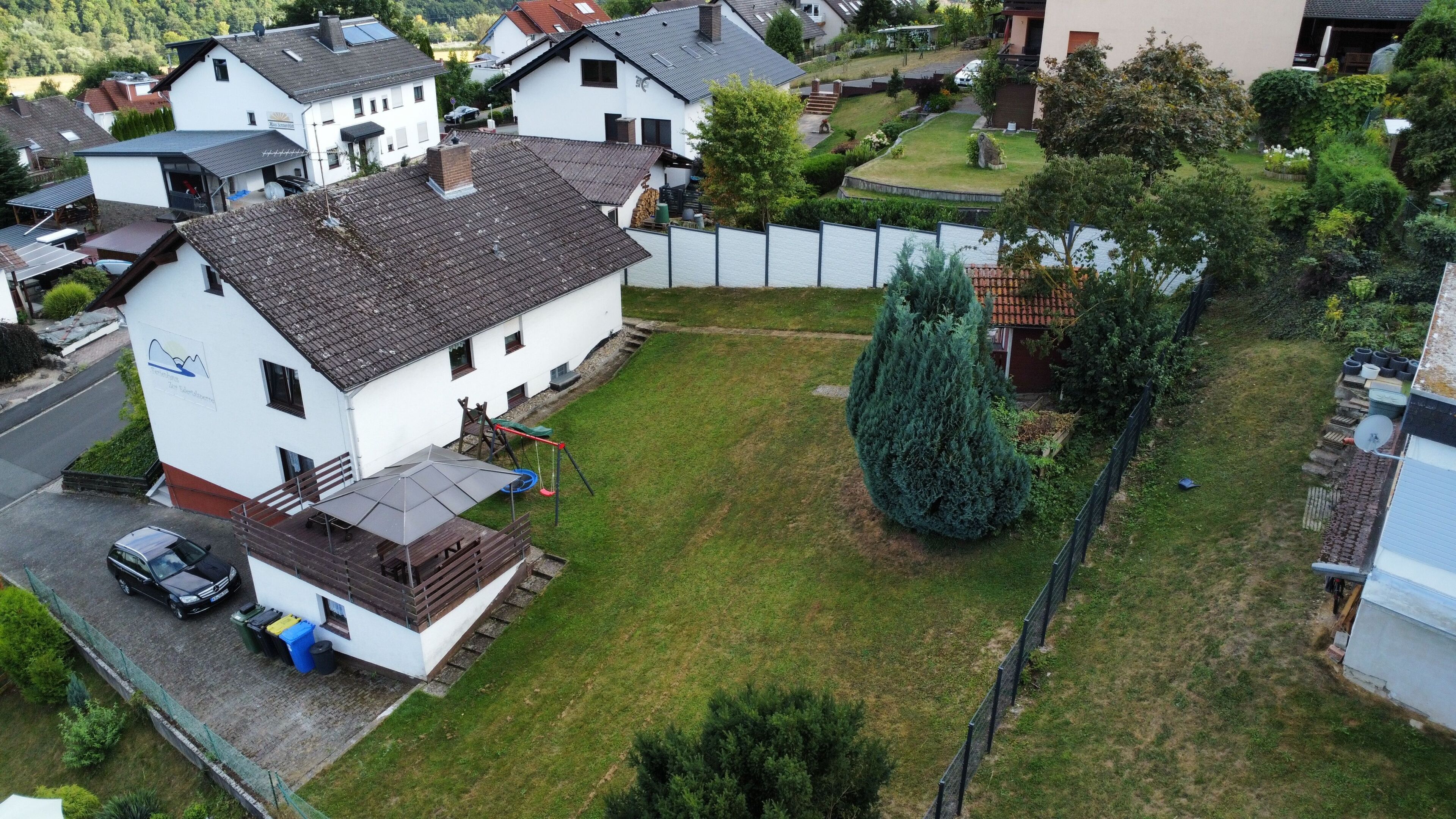 Een woonwijk met huizen, een omheind gazon en een grote naaldboom.