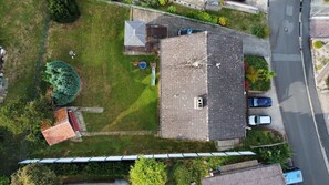 Vista aérea de uma propriedade residencial com telhado inclinado, quintal cercado e rua adjacente.