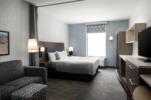 Una habitación de hotel con cama, lámparas de noche, televisor, escritorio y una silla.