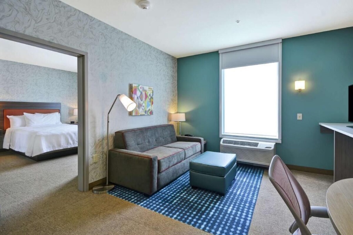 Ein Hotelzimmer mit Bett, Sofa, Schreibtisch und Fenster.