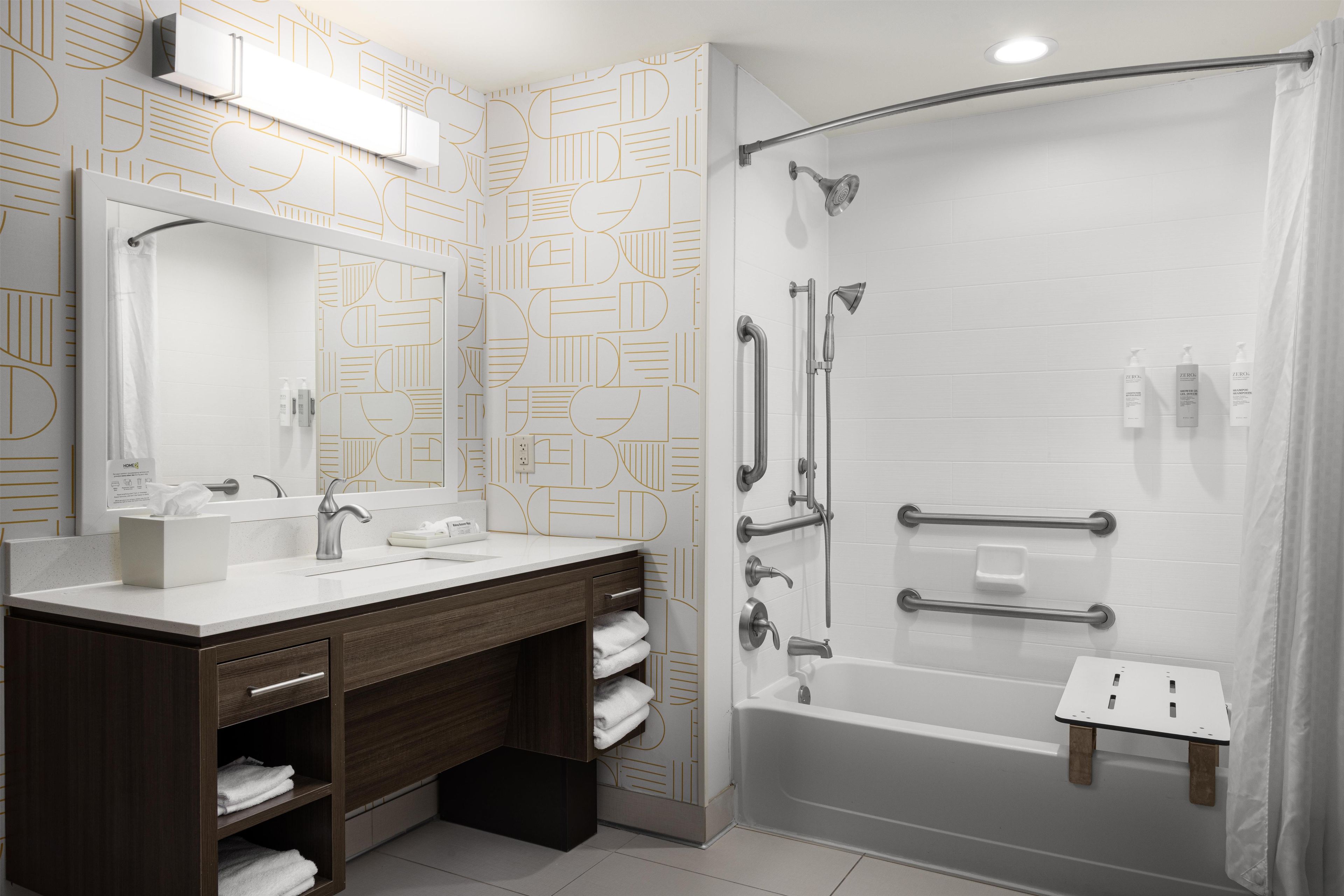 Une salle de bain moderne équipée d’une douche, d’un meuble-lavabo avec un miroir et d’un porte-serviettes.