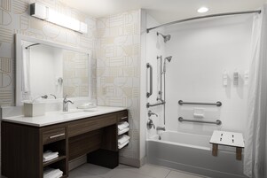 Un baño moderno con ducha, tocador con espejo y un perchero para toallas.