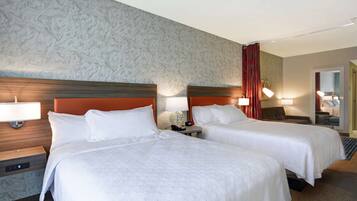 Een hotelkamer met twee bedden, een wand met een marmerlook en een rood gordijn.