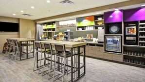 Un espace cuisine moderne avec des tabourets de bar, un coin café et un réfrigérateur.