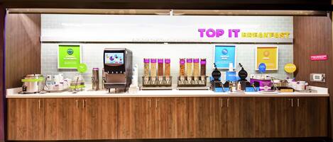 Un espace dédié au petit-déjeuner, avec des distributeurs de yaourt et de flocons d’avoine, une machine à café et divers choix de produits alimentaires.