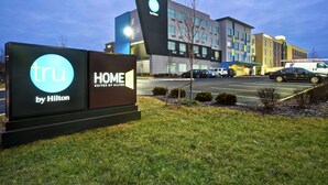 Une enseigne d’hôtel indiquant le nom de l’hôtel (« TRU by Hilton ») et la disponibilité de suites (« HOME SUITES BY HILTON »).