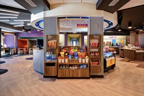 A modern retail kiosk with a variety of snacks and beverages, a check-out counter, and a 'Top It Breakfast' sign in the background. - Tru by Hilton Smyrna Nashville (Smyrna)