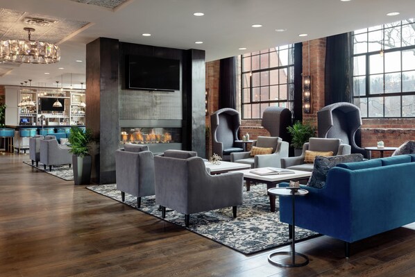 Un área de estar moderna con sofás, sillones, chimenea y una zona de bar con estantes y televisor.