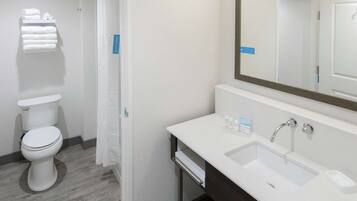 A modern bathroom with a white toilet, a sink with a large mirror, and a towel rack.