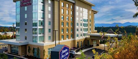 Un hotel moderno con un letrero destacado de Hampton Inn & Suites by Hilton.