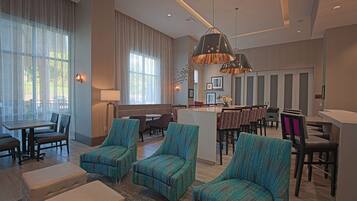 A modern hotel lobby with seating areas, a reception desk, and large windows.