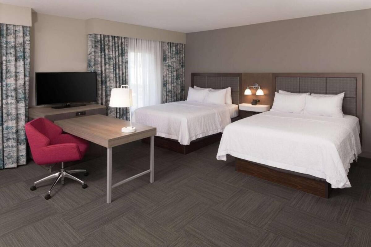 Een hotelkamer met twee bedden, een bureau, een televisie en een stoel.