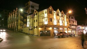 A multi-story building with a traditional architectural style, featuring a prominent entrance with a sign. - Villa Brescia Hotel (Ushuaia)