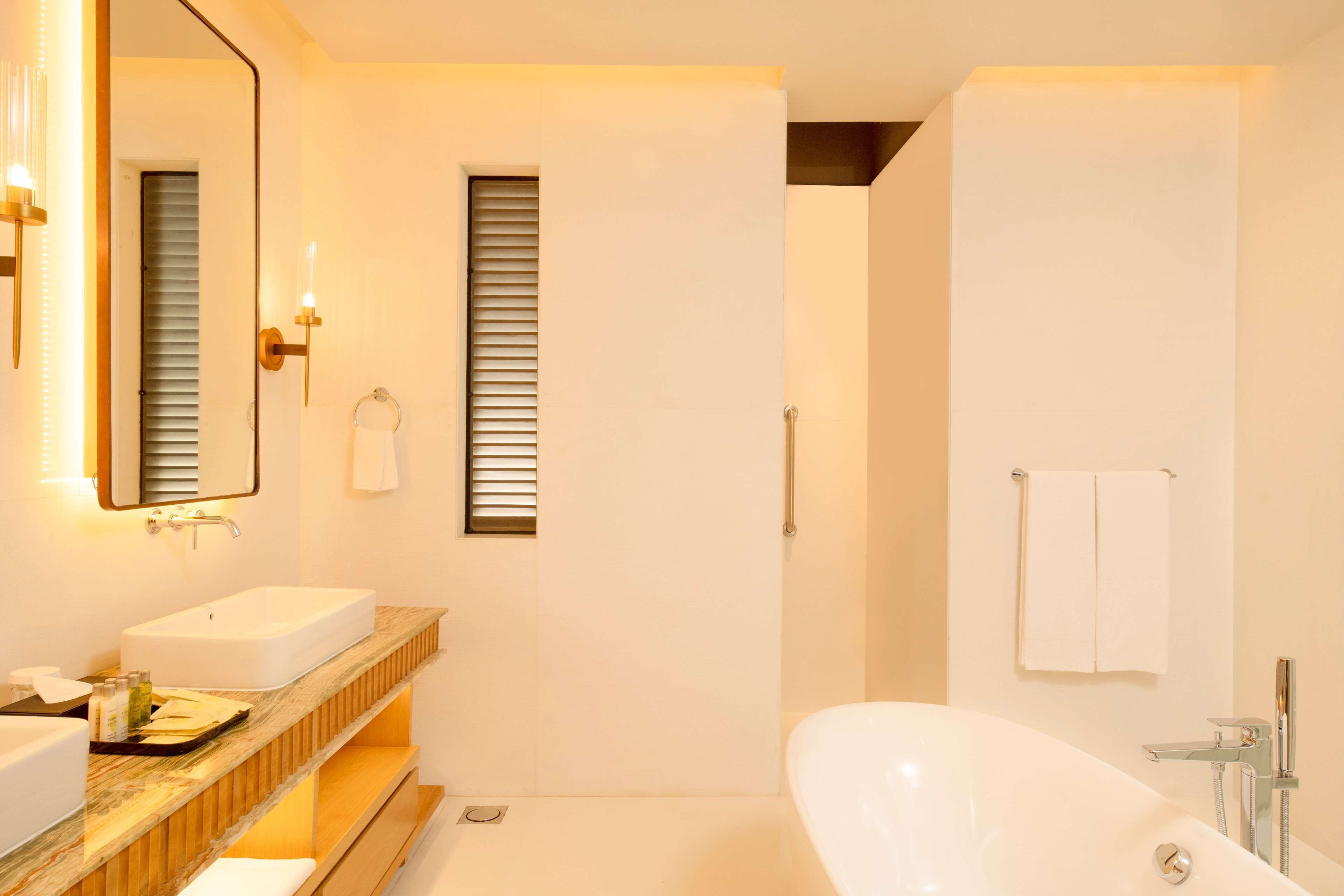 Un baño moderno con una bañera independiente, un espejo grande y un tocador con encimera de mármol.
