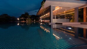 A modern hotel with a large outdoor swimming pool, a covered bar area, and a well-lit exterior. - DoubleTree by Hilton Weerawila Rajawarna Resort (Weerawila)