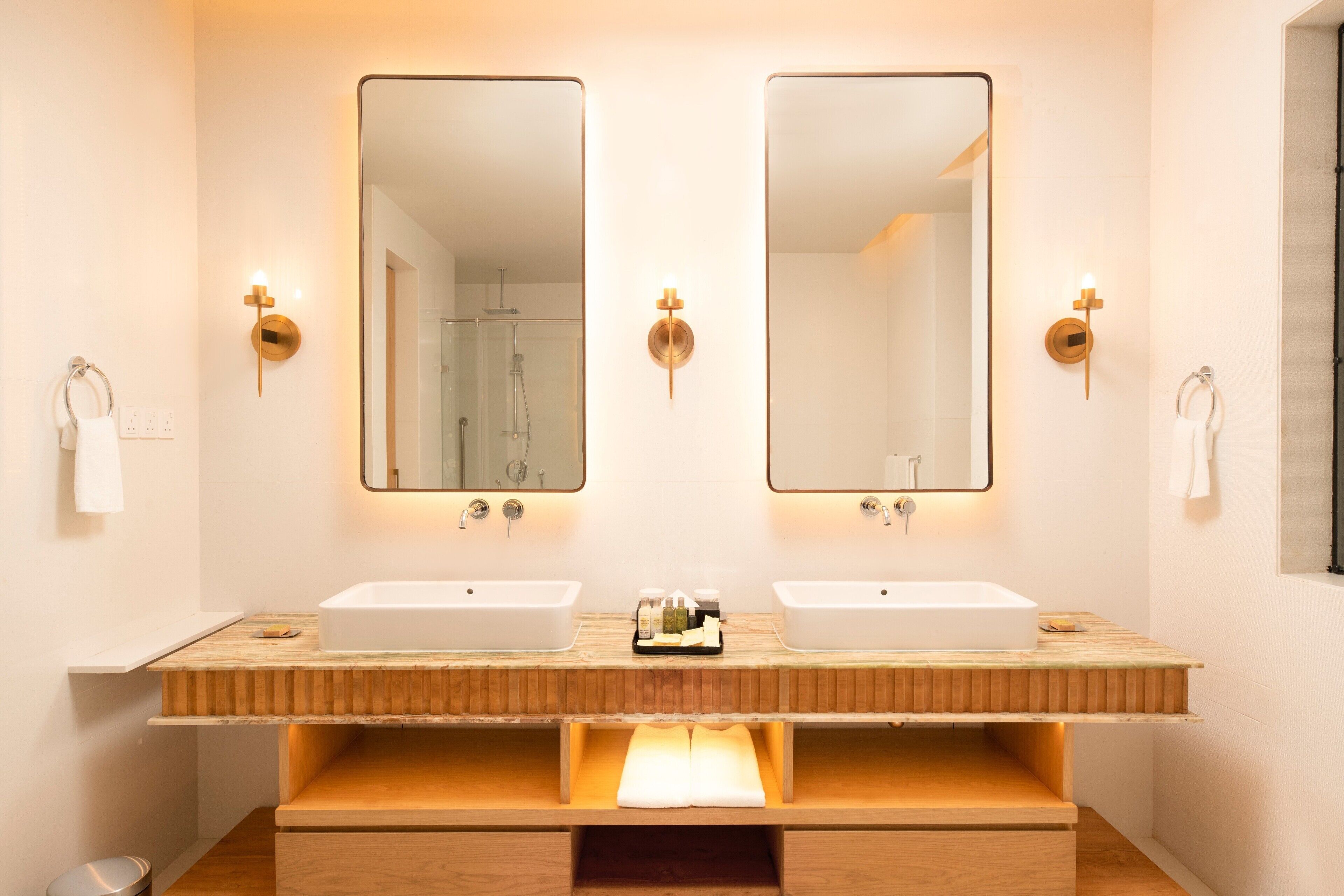 A modern bathroom with two sinks, wooden vanity, and wall-mounted mirrors.