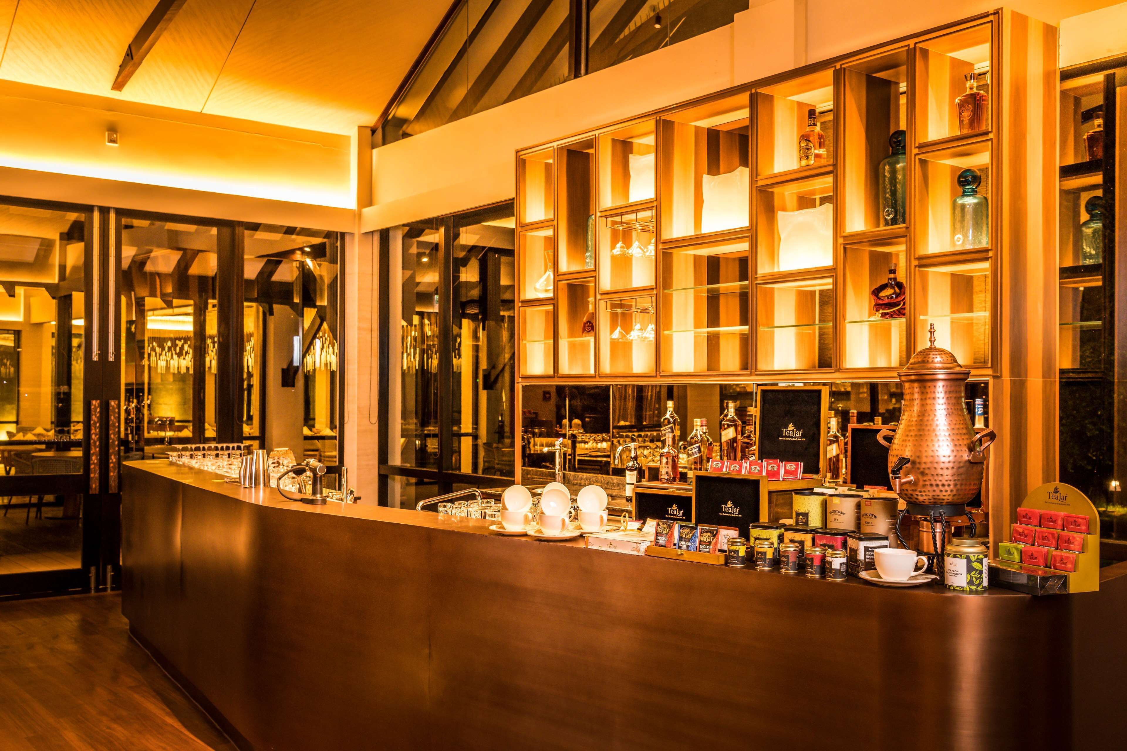 A bar area with shelves of bottles and glasses, a coffee machine, and a counter with cups and saucers.