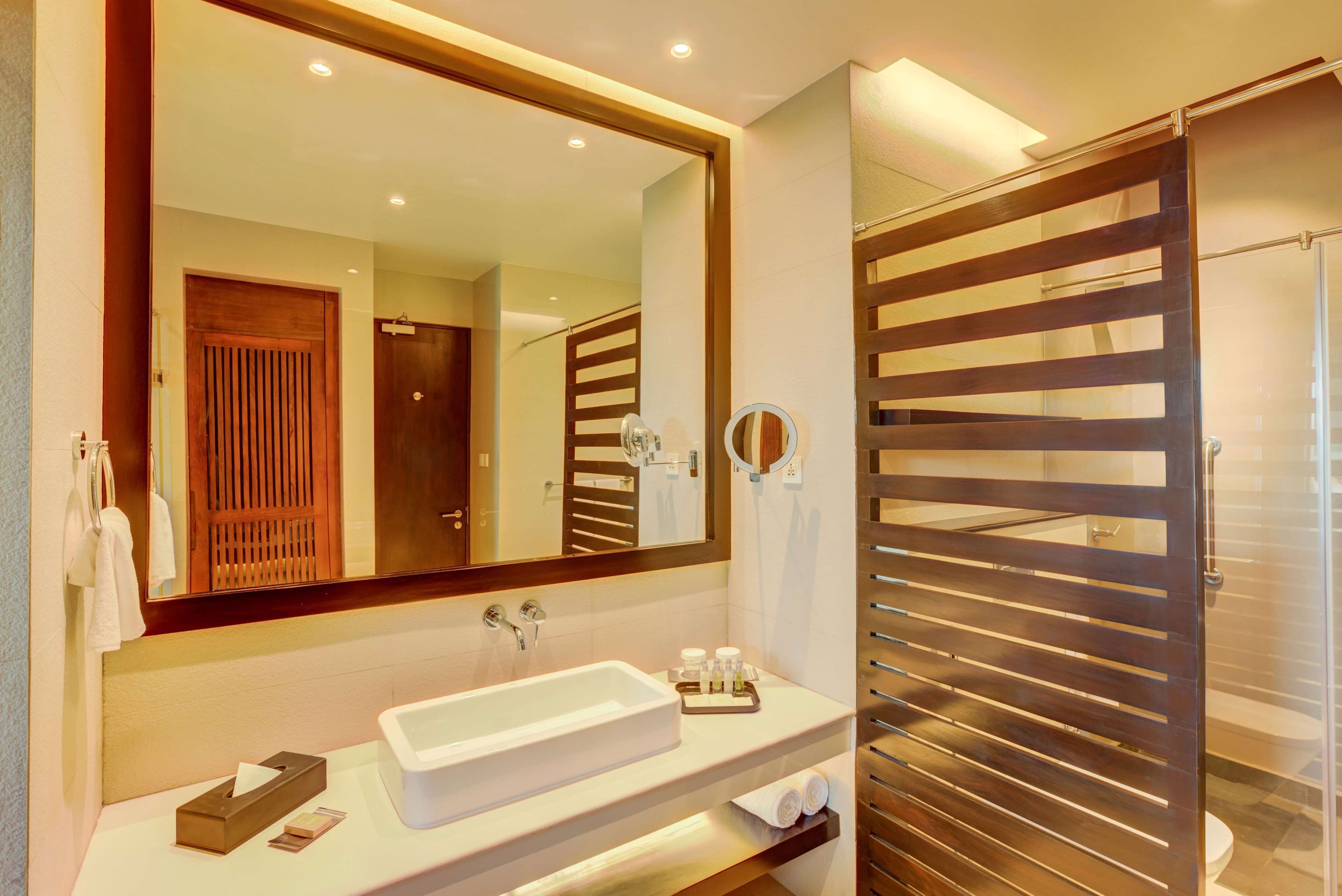 Une salle de bain moderne avec un grand miroir, un lavabo blanc et une cabine de douche en bois.