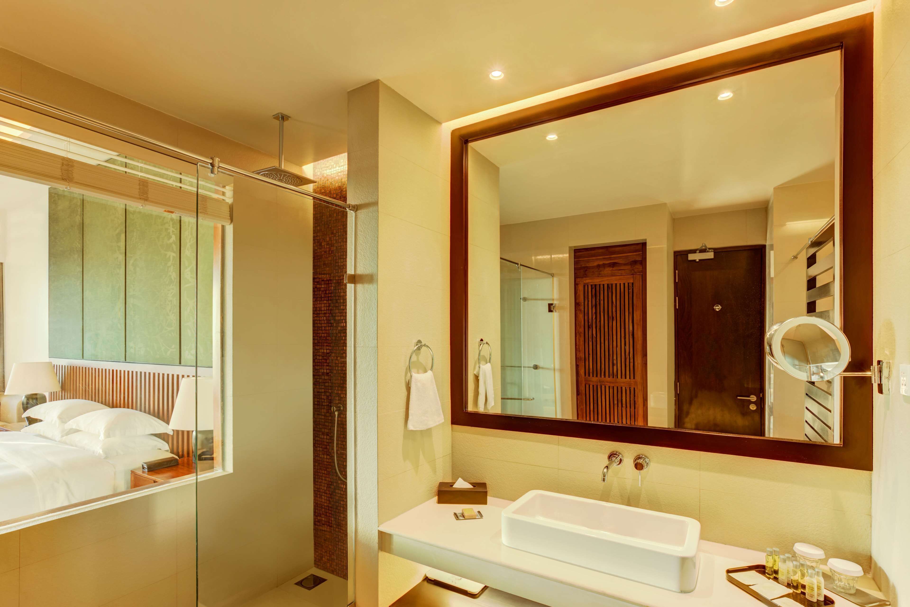 Un baño moderno con un espejo grande, un lavabo blanco y una zona de ducha.