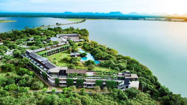 A resort with a swimming pool, lush greenery, and a view of a large lake and mountains. - DoubleTree by Hilton Weerawila Rajawarna Resort (Weerawila)