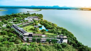 A resort with a swimming pool, lush greenery, and a view of a large lake and mountains. - DoubleTree by Hilton Weerawila Rajawarna Resort (Weerawila)