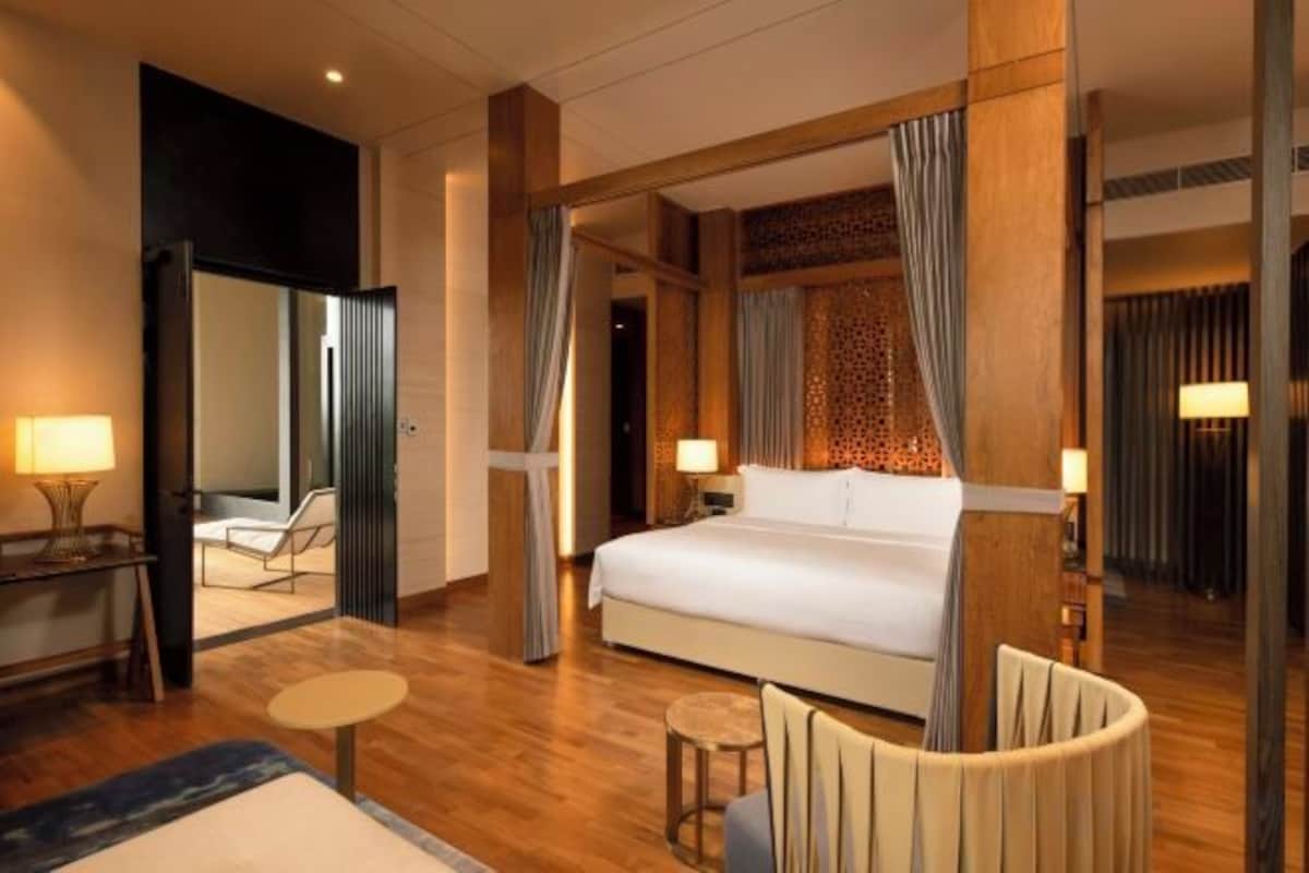 A hotel room with a large bed, a sitting area with a table, and a mirror.