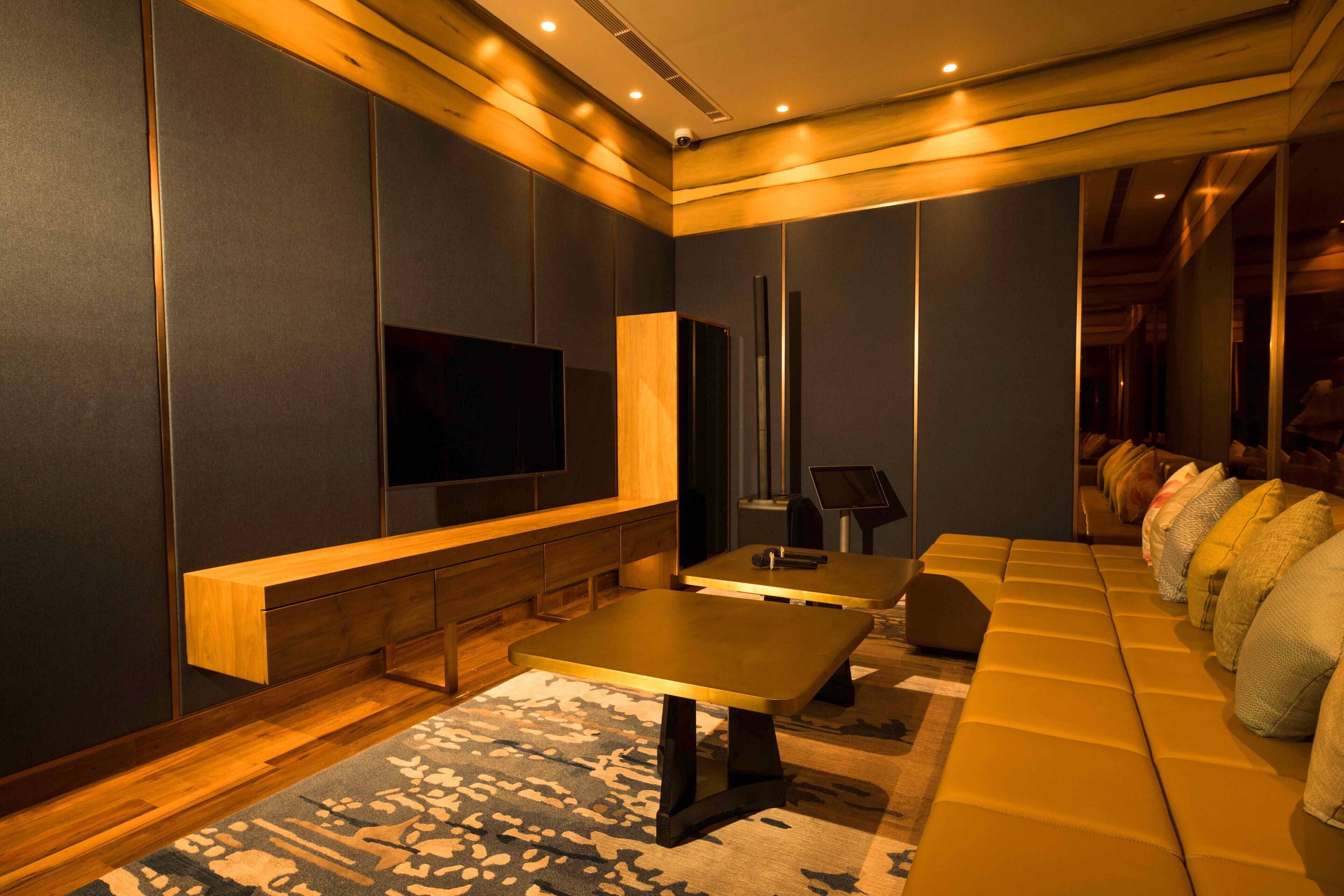 A modern interior with a long sofa, a wooden bench, and a flat-screen TV mounted on the wall.