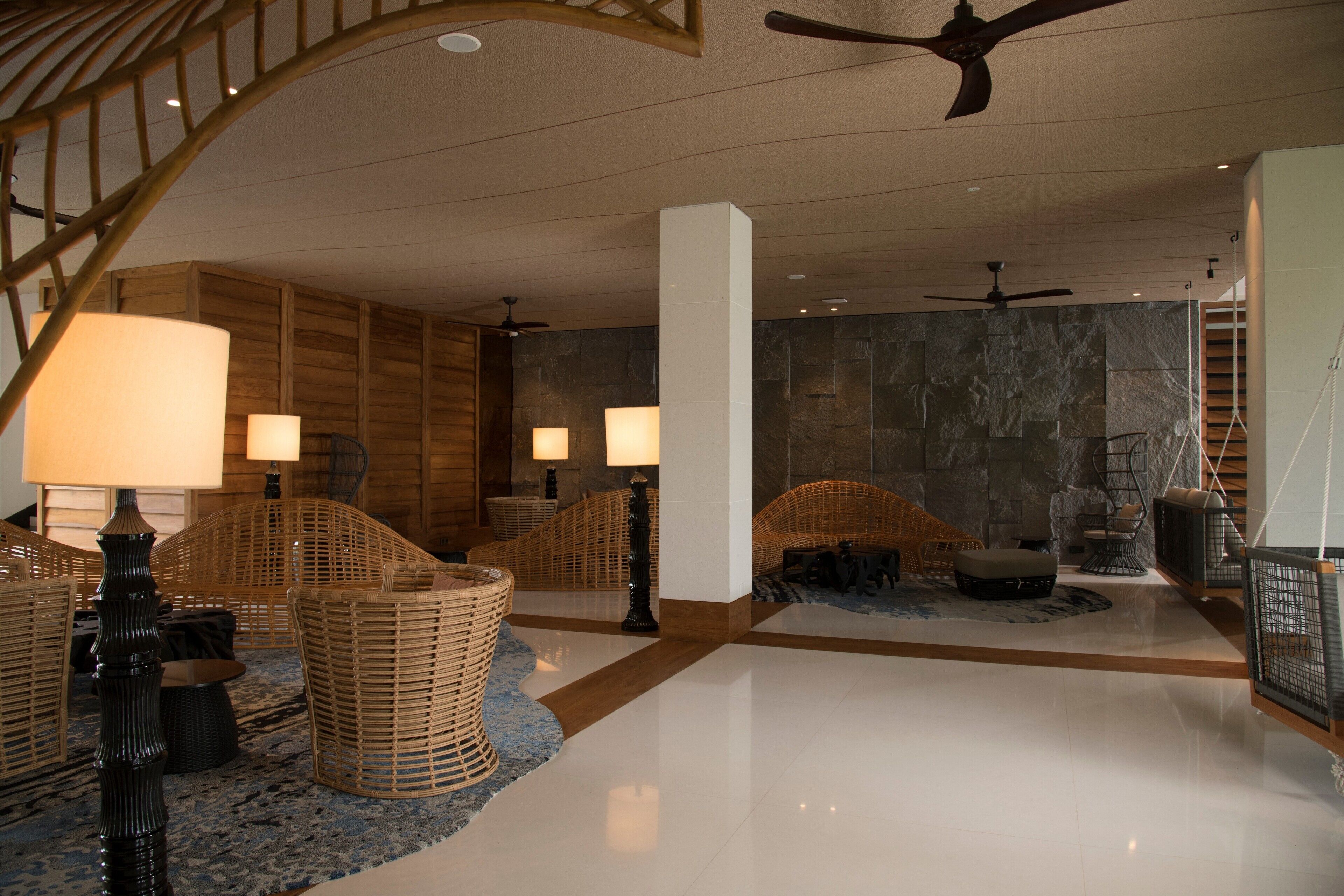 A spacious lobby with wicker furniture, a polished floor, and a stone wall.