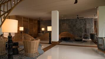 A spacious lobby with wicker furniture, a polished floor, and a stone wall.