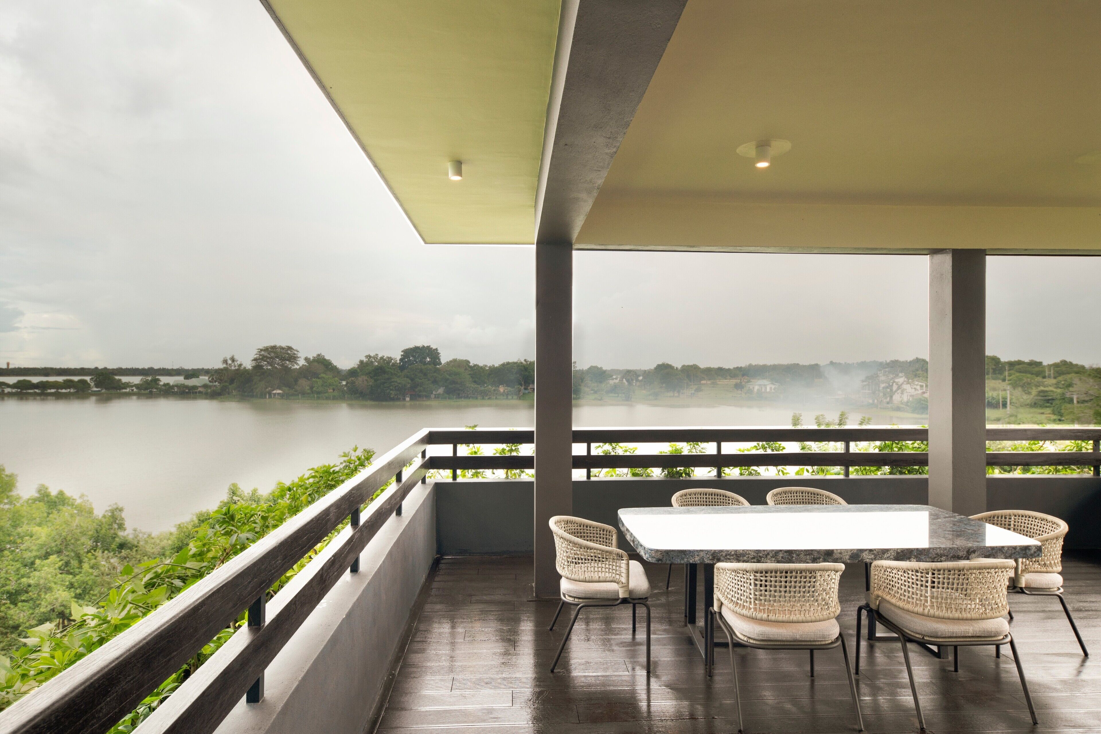 A terrace with a table and chairs overlooking a lake.